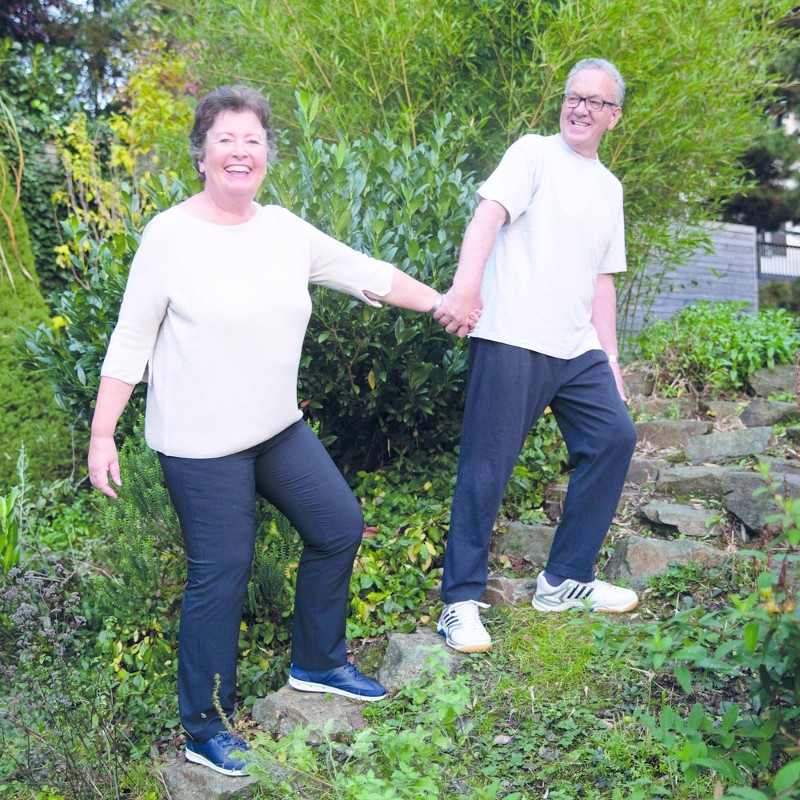 Älteres Paar geht lachend über Stufen im Garten.“ / Credit: ÖGK/Yvonne_Kreuzmayr