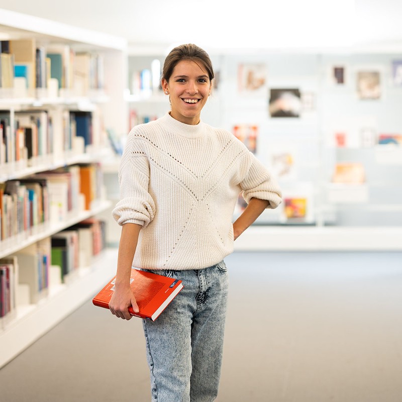 Studentin mit Buch in der Bibliothek / Credit: ÖGK