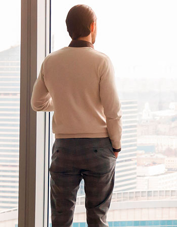 Mann blickt durch Fenster auf Stadt, Foto: fizkes/Shutterstock.com