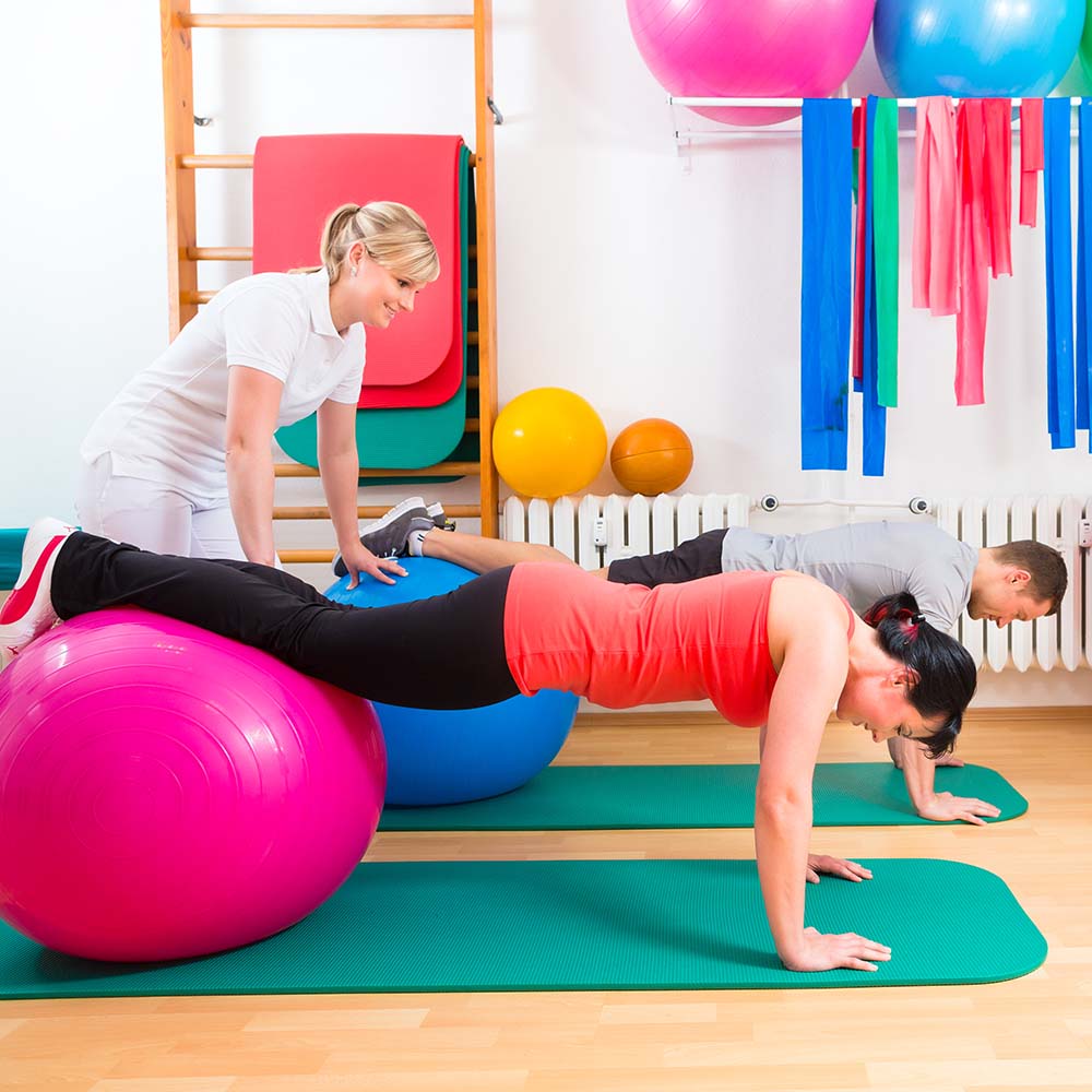 Therapeutin zeigt Patient Übungen am Gymnastikball / Credit: shutterstock.com/Kzenon