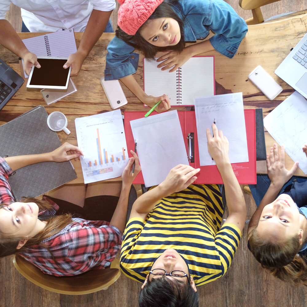 Studierende sitzen über Unterlagen / Credit: intuon gunnin/shutterstock.com