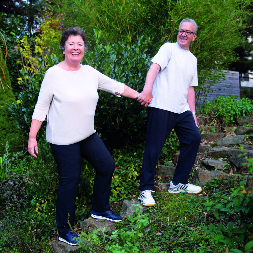 Älteres Ehepaar geht lachend über Stufen im Garten / Credit: ÖGK/Yvonne_Kreuzmayr