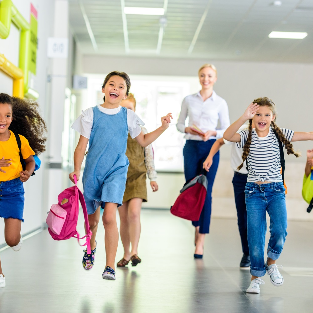 Schüler laufen in der Schule mit Lehrer im Hintergrund / Credit: LightField Studios / Shutterstock 1162595155