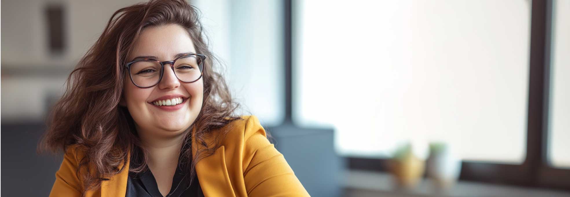 Lachende junge Frau mit Brille und gelber Jacke